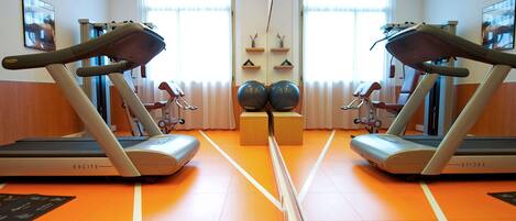A gym with two treadmills, orange flooring, and large windows.