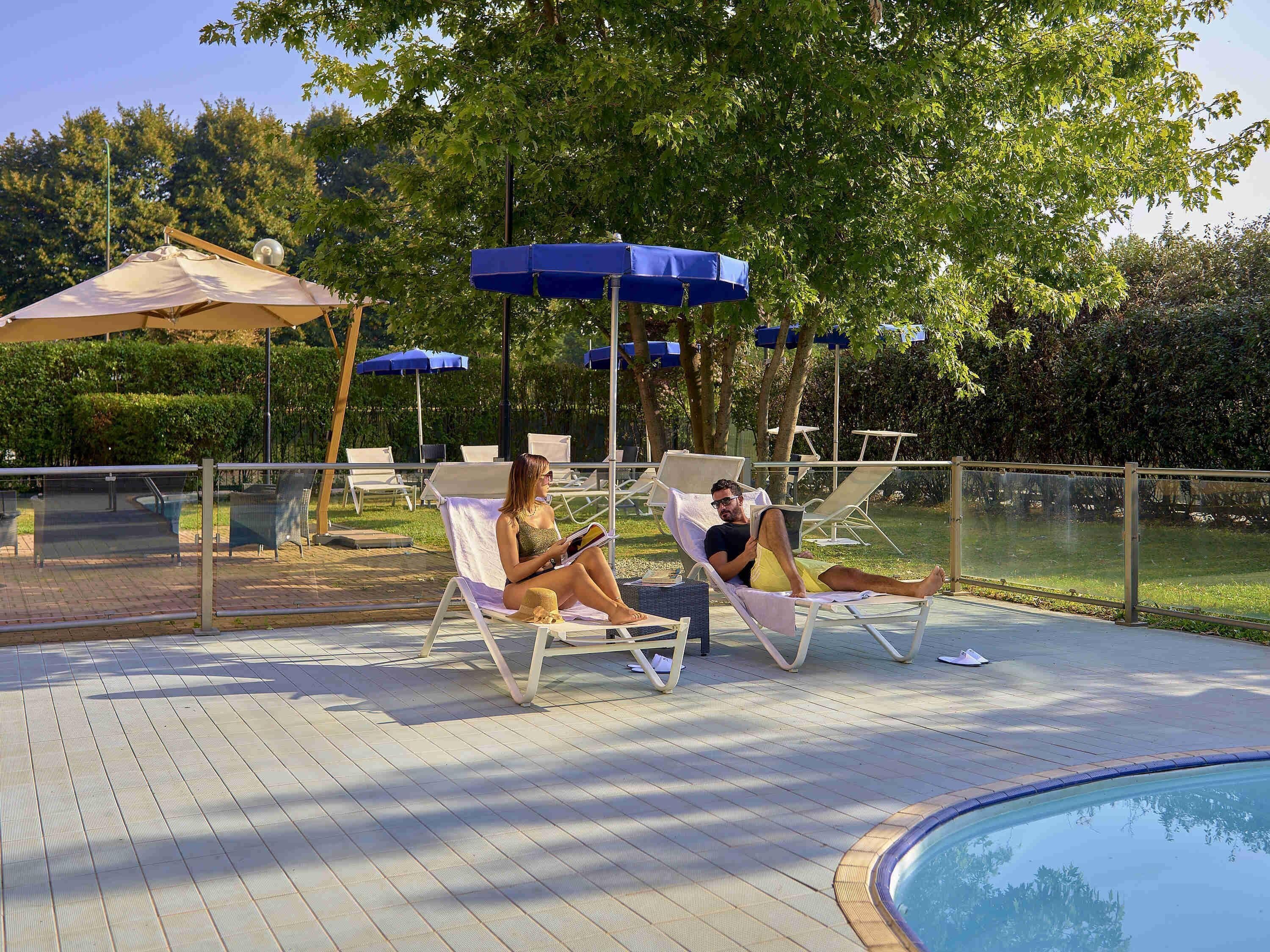 A poolside area with lounge chairs, umbrellas, and a pool.