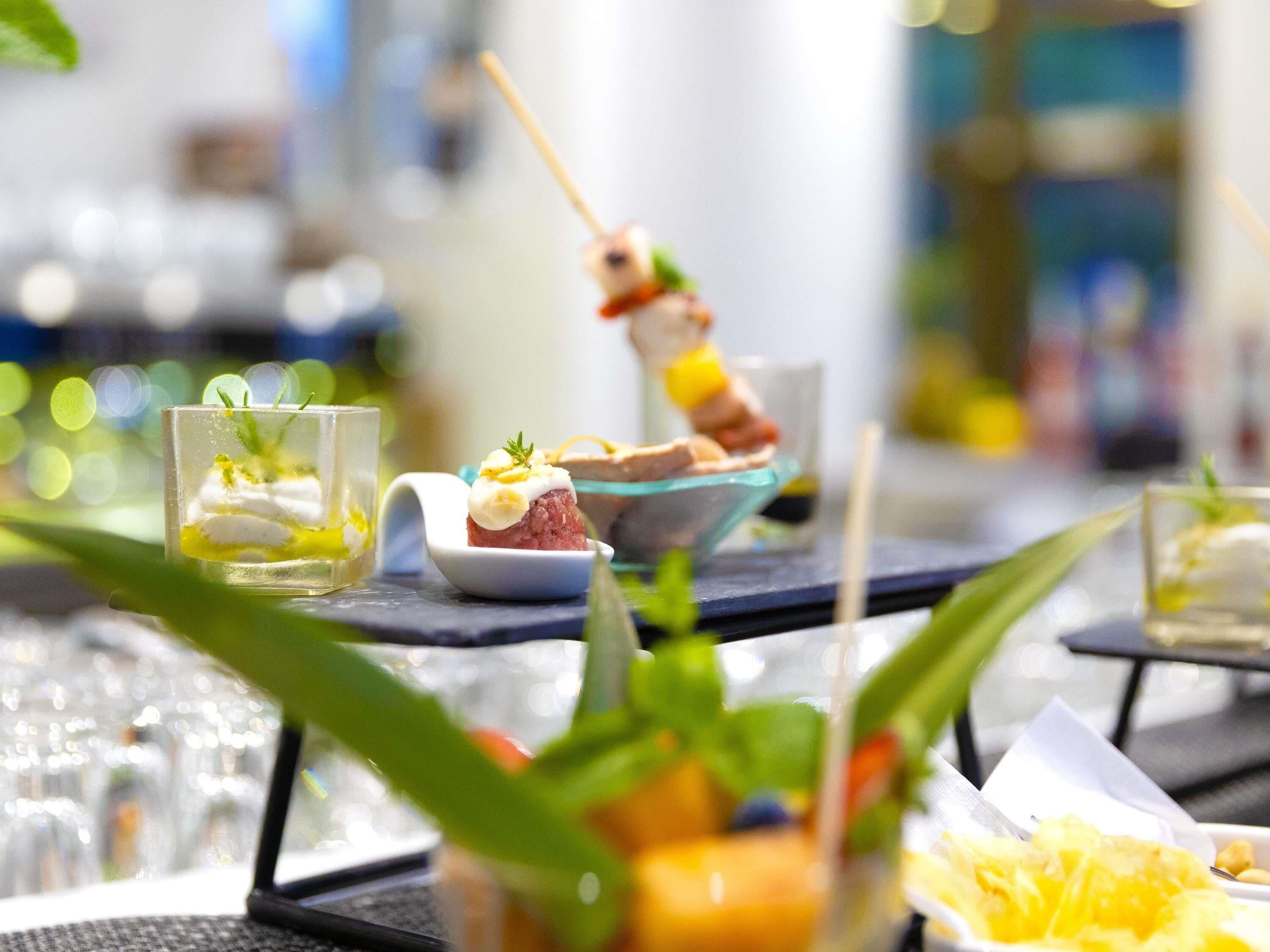 A dining area with a glass table set for a meal, featuring a dish with a skewer and a bowl of food.