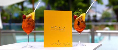 Two cocktails on a table with a yellow menu in the center.