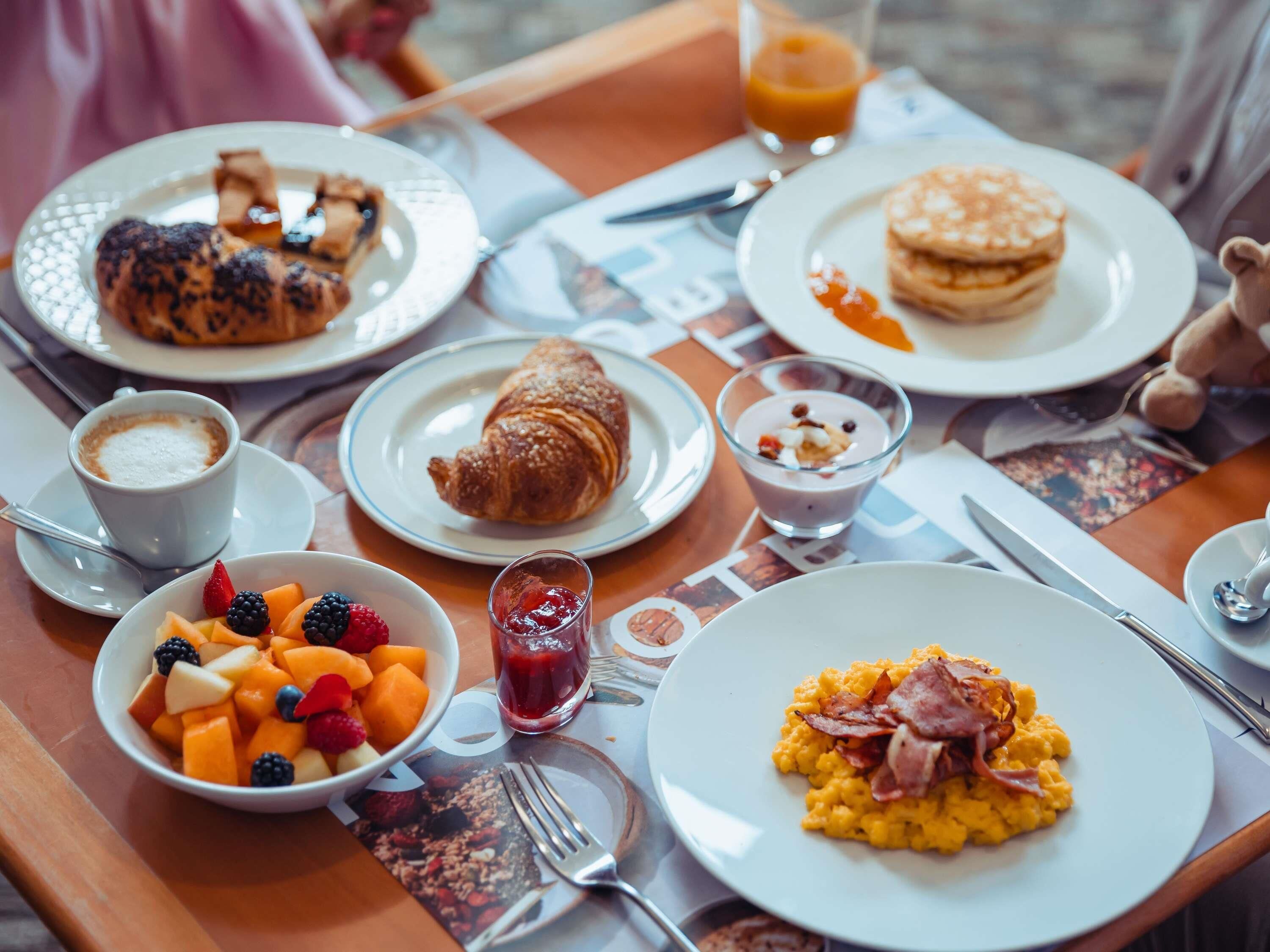 Colazione con croissant, pancake, uova strapazzate e frutta.