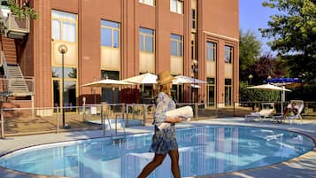 Una piscina al aire libre, sombrillas, sillones reclinables de piscina