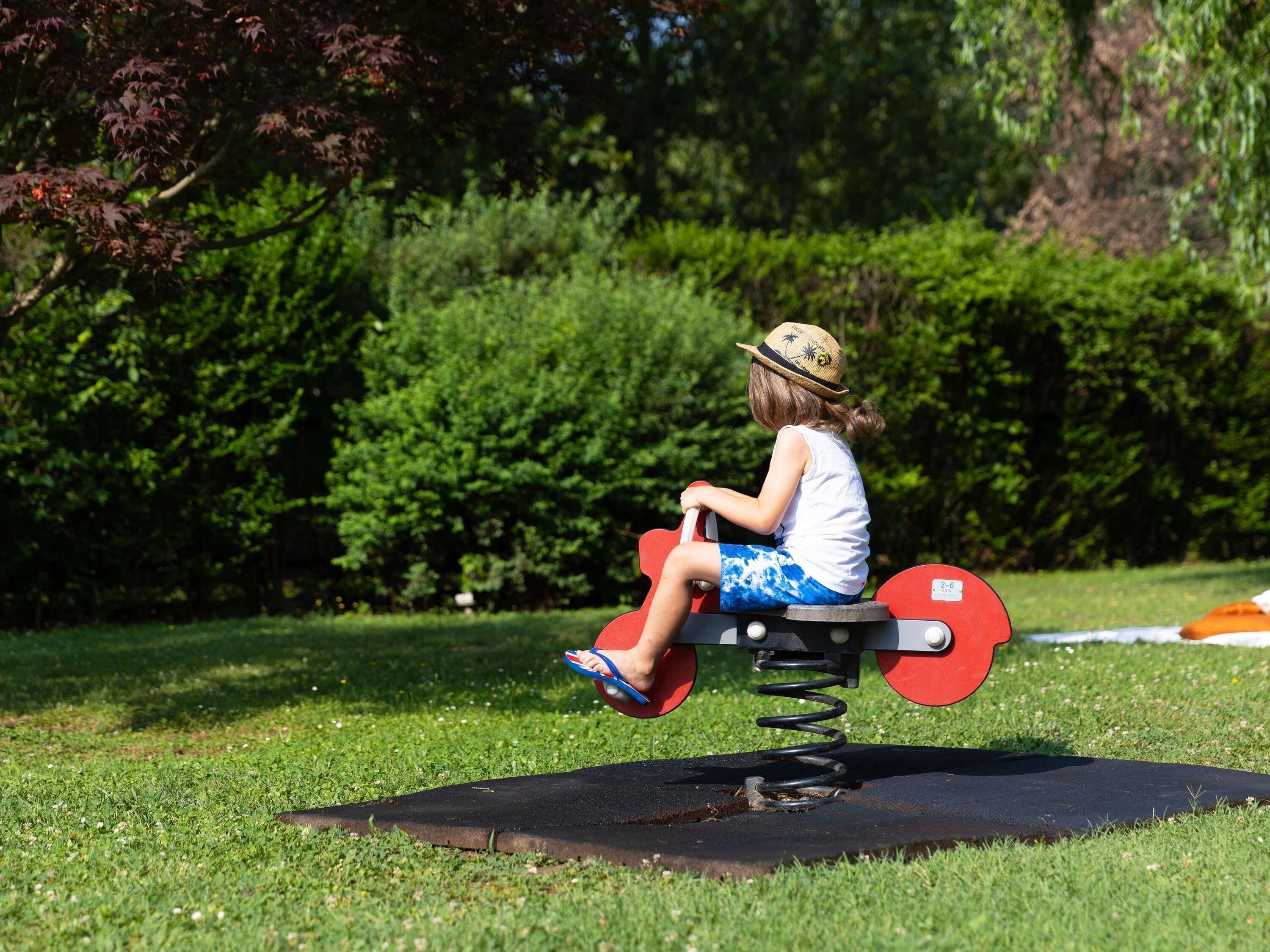 A child on a stationary exercise equipment in a park.