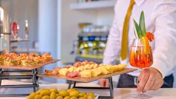 A bar setting with a bartender holding a cocktail, and two platters of appetizers.