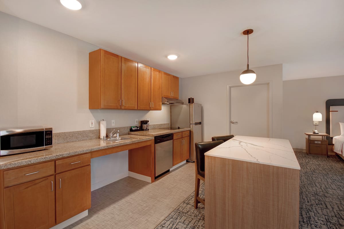 A modern kitchen with wooden cabinets, stainless steel appliances, and a marble countertop.