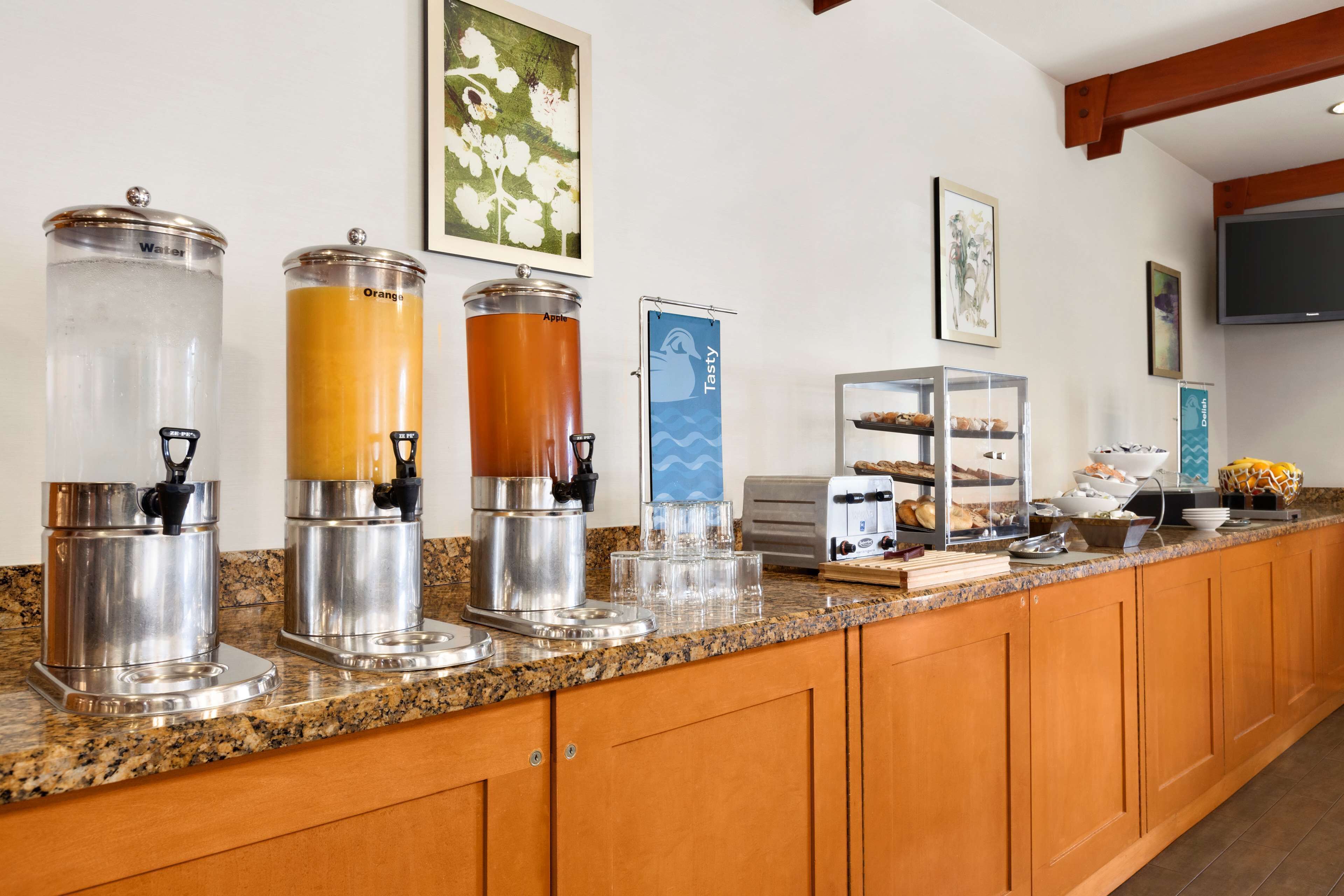 A buffet setup with juice dispensers labeled 'Water,' 'Orange,' and 'Apple.'