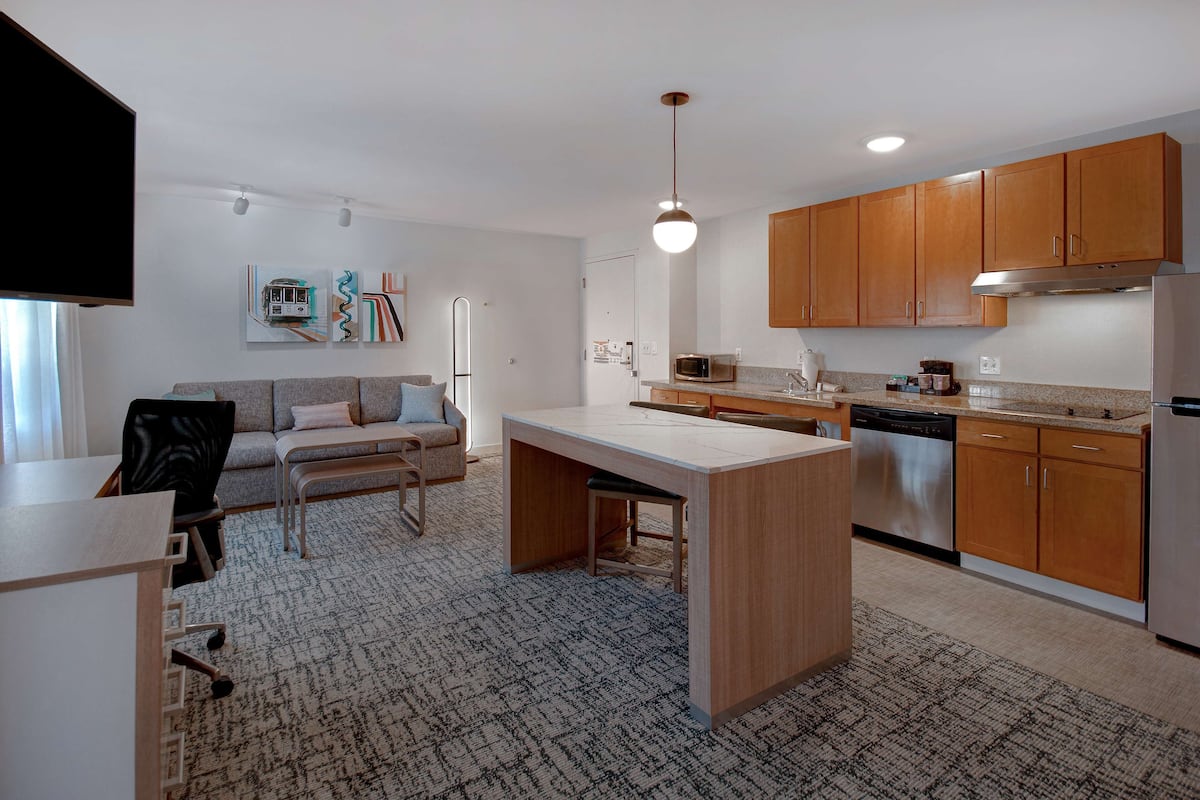 A modern kitchen with wooden cabinets, a built-in oven, and a microwave.