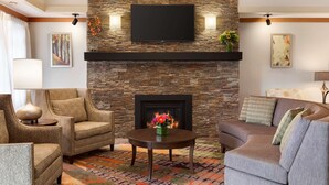 Una sala de estar con pared de piedra, chimenea y televisor de pantalla plana montado encima.