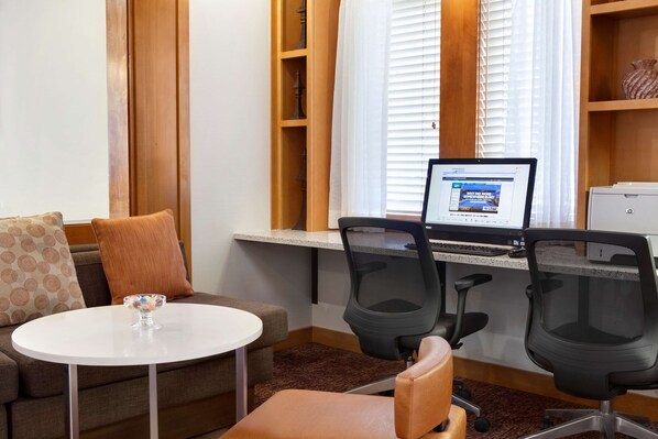 A workspace with two office chairs, a computer, and a small table with a bowl of fruit.