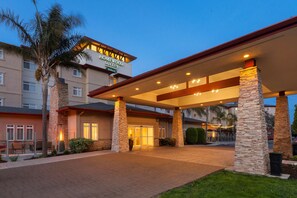 A hotel entrance with a covered walkway, stone pillars, and palm trees. - Homewood Suites by Hilton San Francisco Airport North (Brisbane)