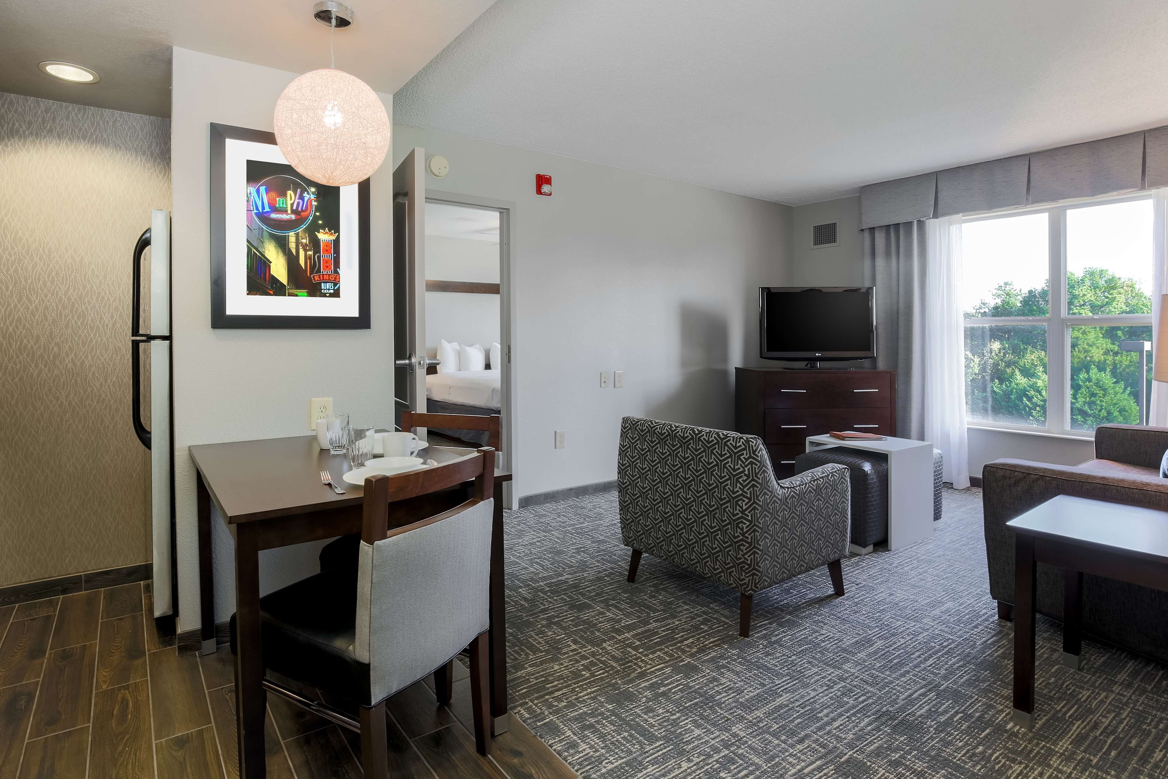 A hotel room with a dining area, a TV, and a large window with a view.