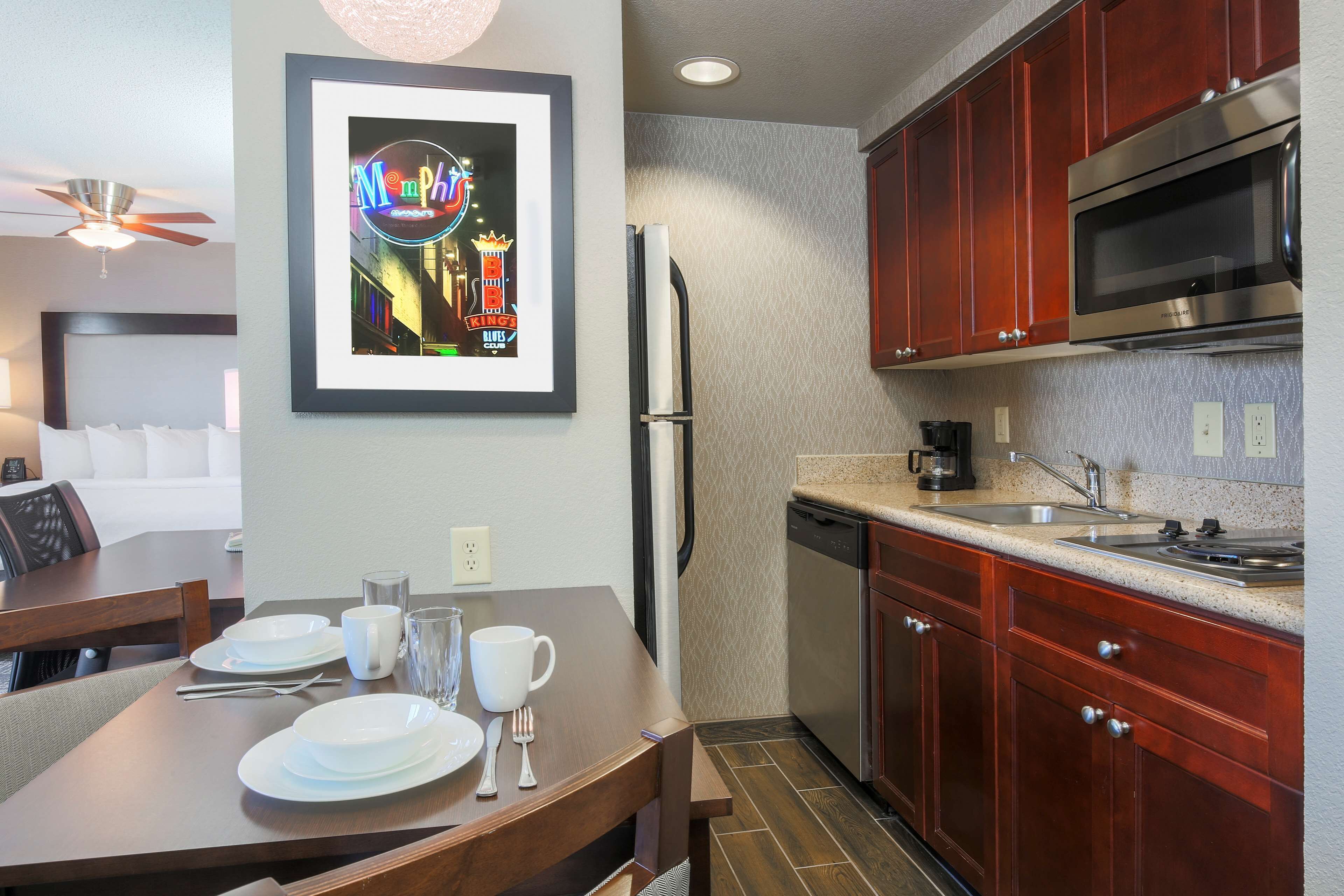 A modern kitchen with wooden cabinets, a stainless steel refrigerator, and a microwave.