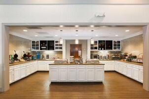 A spacious kitchen with white cabinetry, a central island, and pendant lighting.