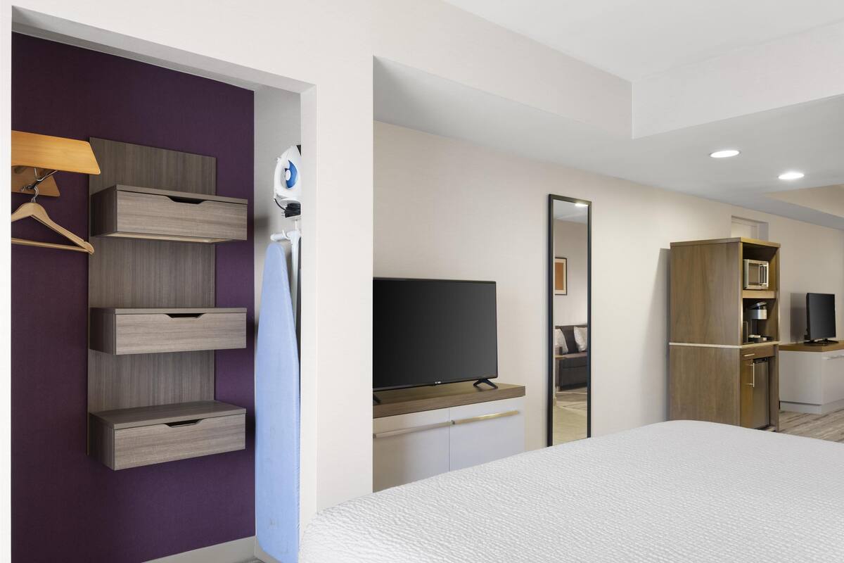 A hotel room with a bed, a TV, a wardrobe, and a mirror.