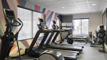 Une salle de sport équipée de tapis de course, de vélos d’appartement et de matériel de musculation.