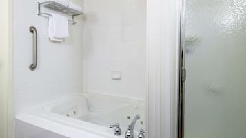 A bathroom with a bathtub, a handrail, and a towel rack.