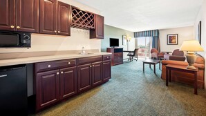 Une chambre d’hôtel compacte équipée d’une kitchenette, d’un téléviseur à écran plat, d’un canapé et d’une lampe.