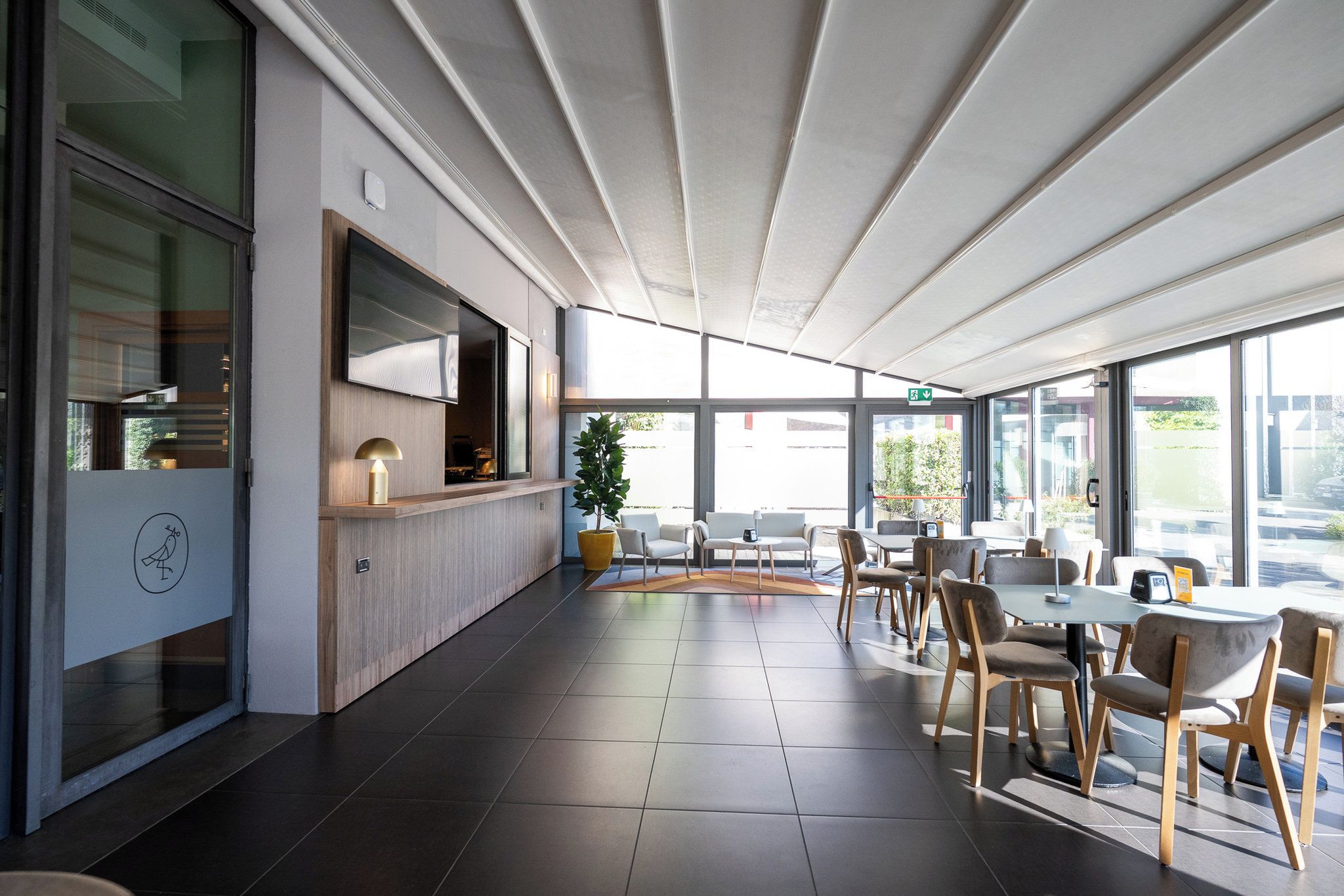 A modern indoor space with a seating area, a counter, and large windows.