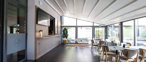 A modern indoor space with a seating area, a counter, and large windows.