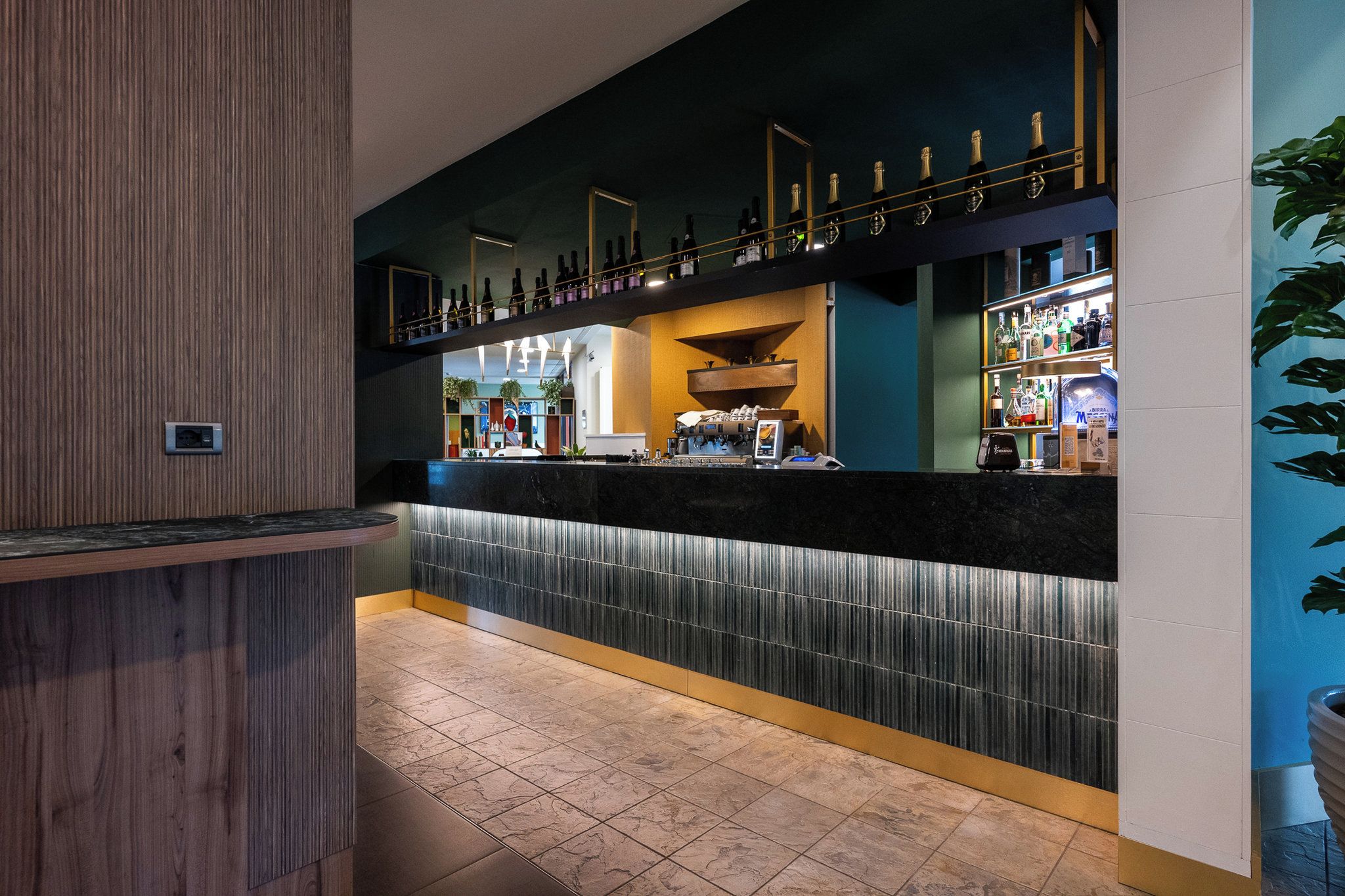 Eine Bar mit einer Theke, Regalen voller Flaschen und einer Sitzgelegenheit.