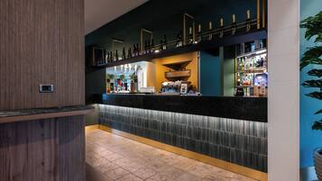 Eine Bar mit einer Theke, Regalen voller Flaschen und einer Sitzgelegenheit.