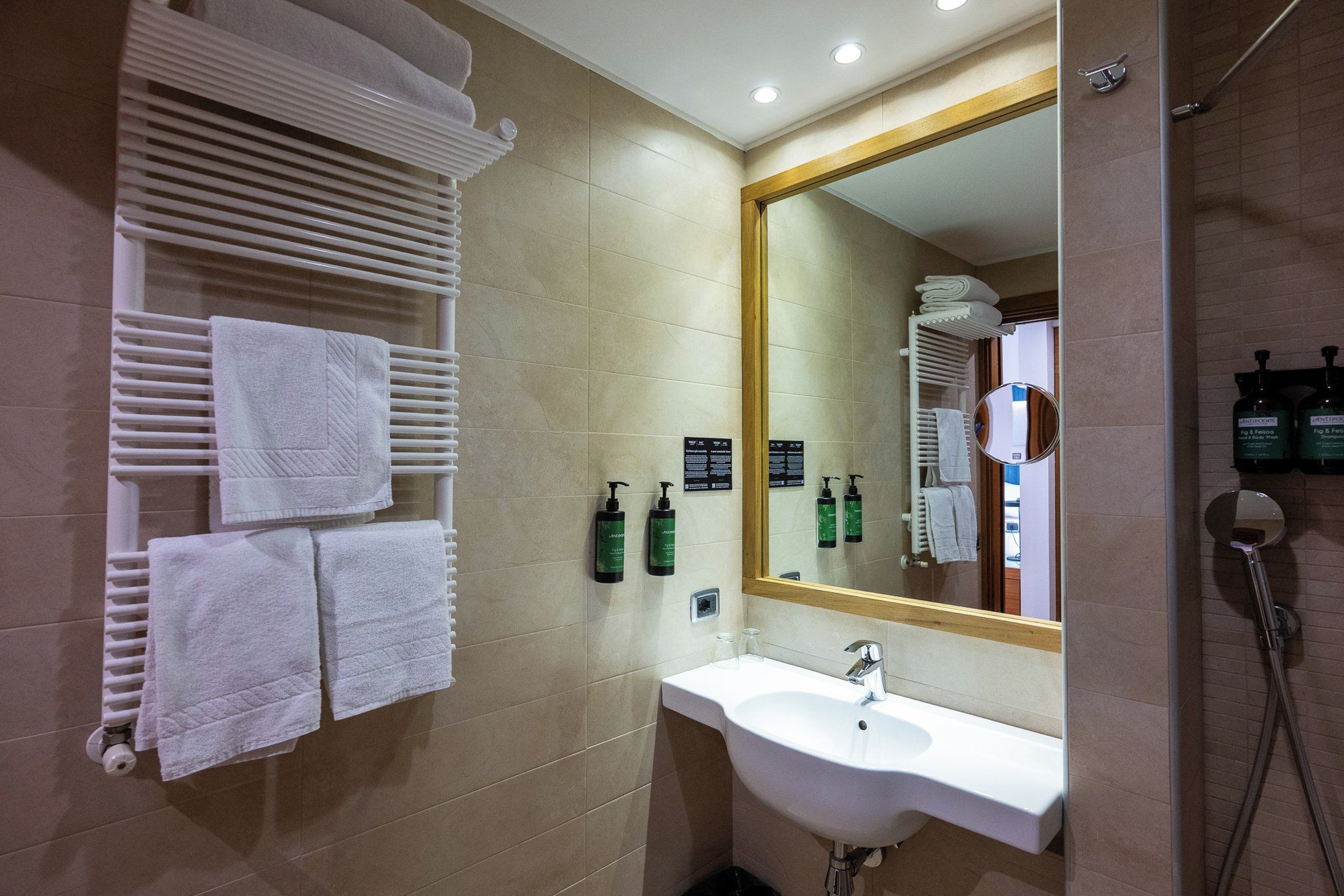 Un baño de hotel con lavamanos, espejo, toallero y artículos de aseo.