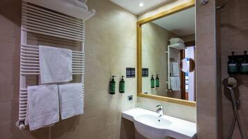 Un baño de hotel con lavamanos, espejo, toallero y artículos de aseo.