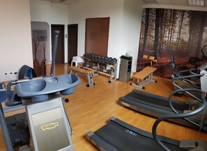 Un gimnasio con cintas de correr, una máquina de remo, mancuernas y bancos.