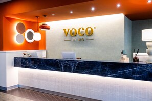 A reception desk with a marble top, a logo above it, and a modern light fixture on the ceiling.