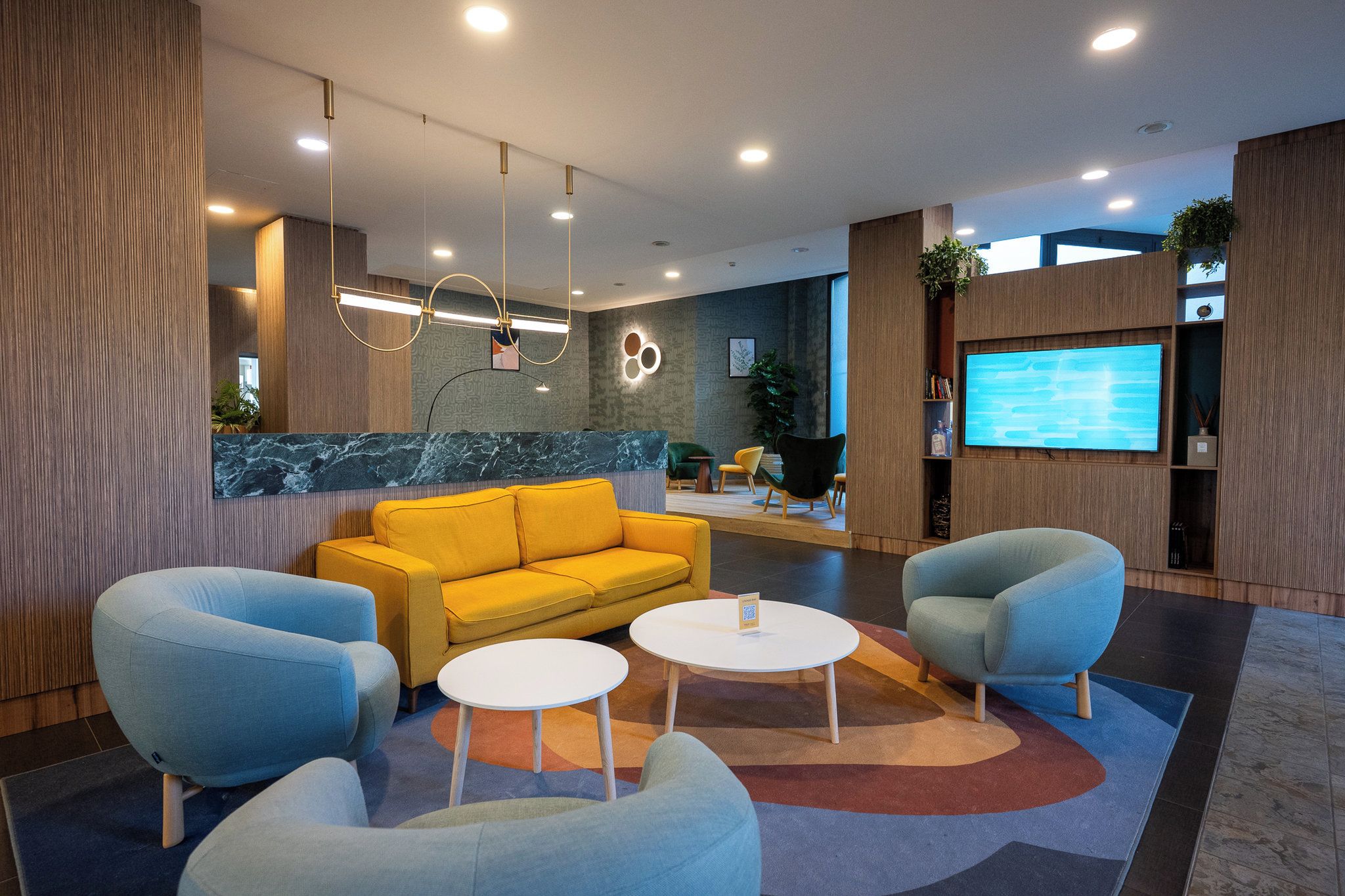A modern lobby with a yellow sofa, two armchairs, and a coffee table.