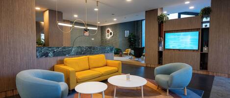 A modern lobby with a yellow sofa, two armchairs, and a coffee table.