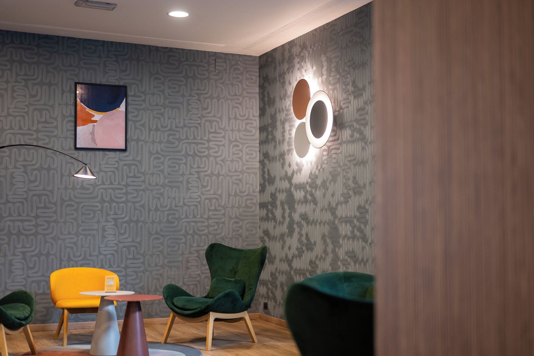 A modern interior with patterned wallpaper, a framed artwork, and a unique circular light fixture.