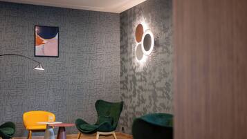 A modern interior with patterned wallpaper, a framed artwork, and a unique circular light fixture.