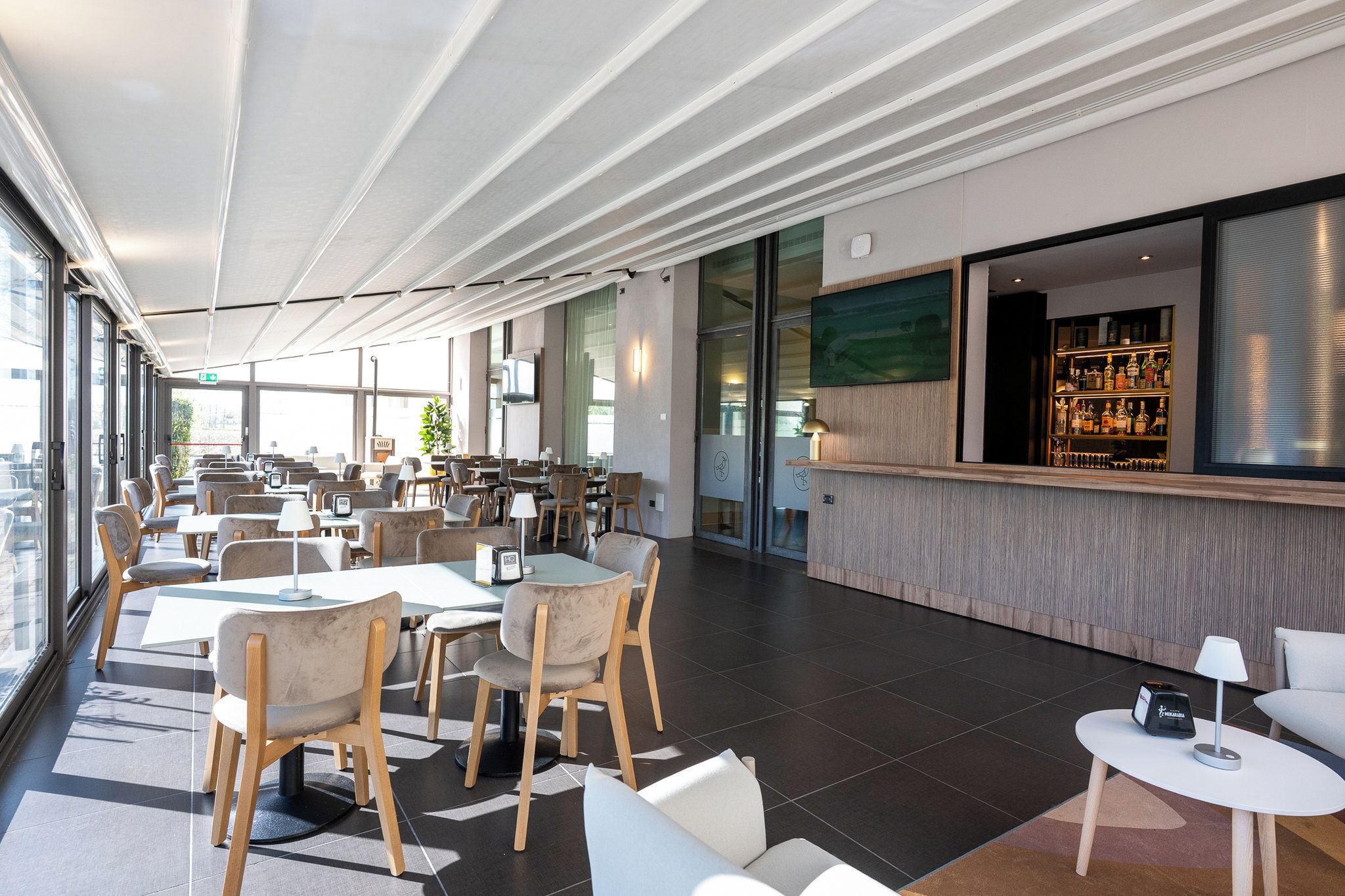 Un moderno vestíbulo de hotel con zona de bar, arreglos de asientos y grandes ventanales.