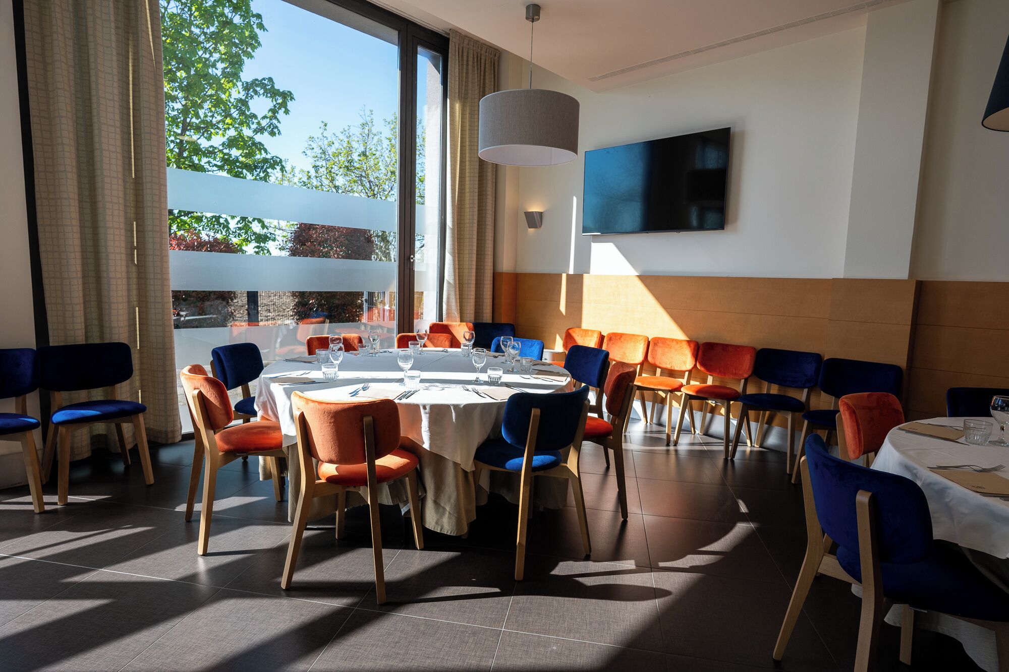 A dining area with a round table, chairs, and a TV on the wall.