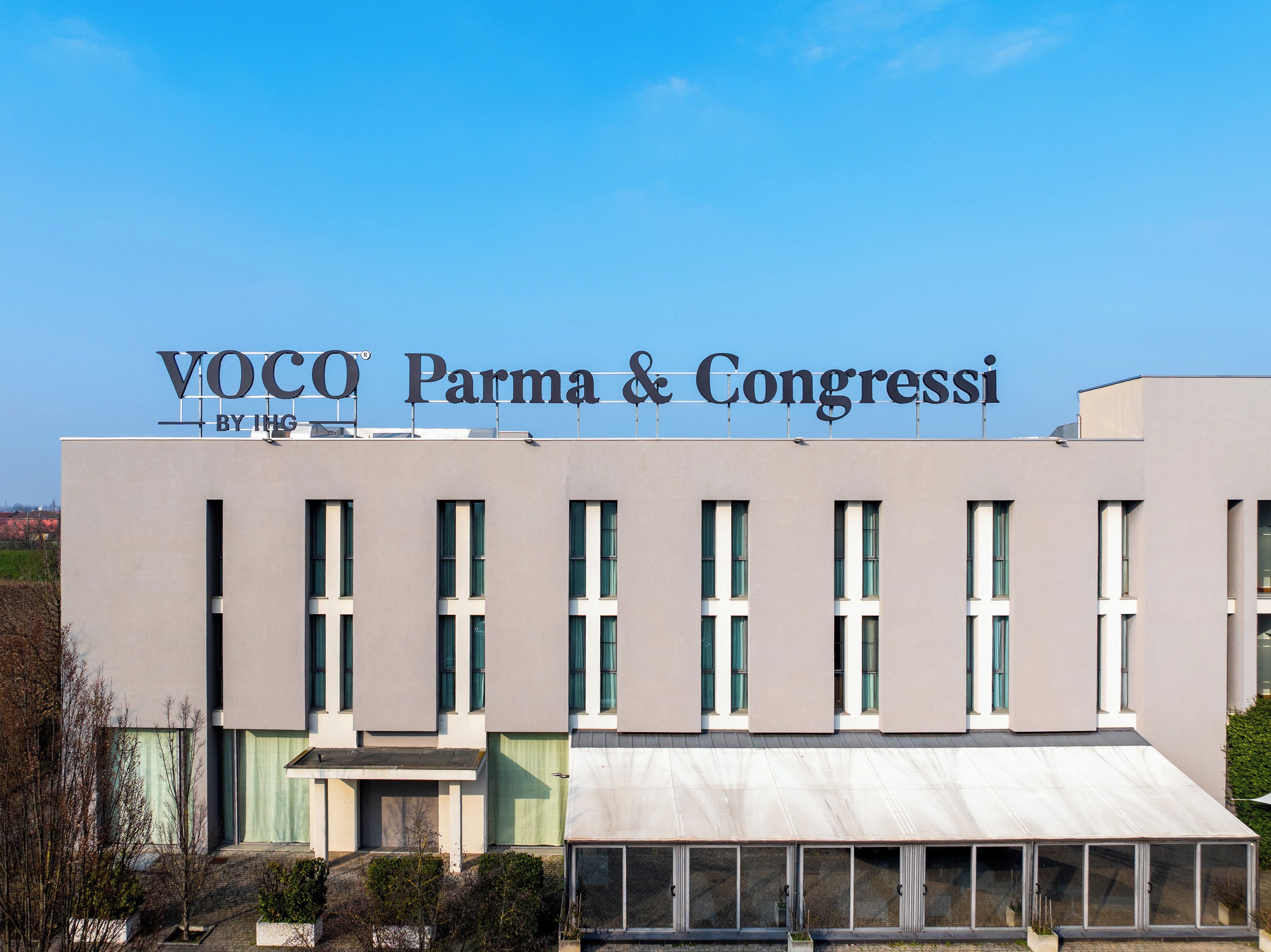 Un edificio moderno con il cartello 'VOCO® Parma & Congressi' sul tetto.