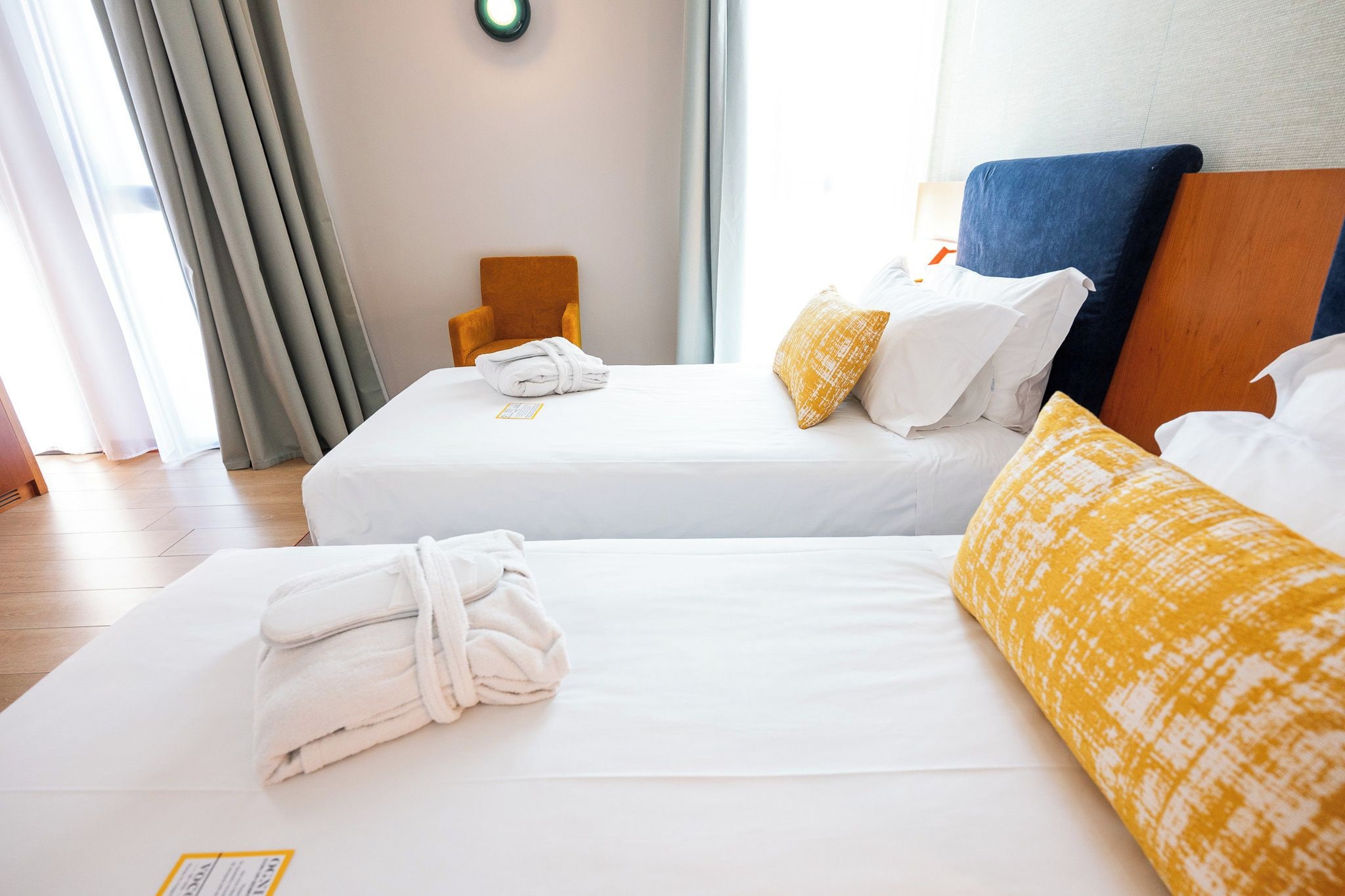 A hotel room with two beds, a wooden headboard, and a window with curtains.