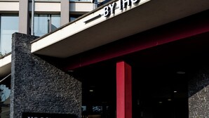 Un edificio con un cartel que dice 'VOCO BY HG' y banderas de la Unión Europea e Italia.