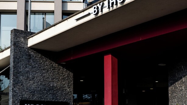 A building with a sign reading 'VOCO BY HG' and flags of the European Union and Italy. - voco Parma Congressi by IHG (Parma)