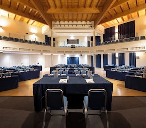 A conference room with multiple tables, chairs, and a balcony with blue curtains. - voco Parma Congressi by IHG (Parma)