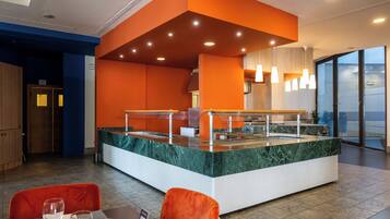 Un restaurante moderno con una isla central, zona de estar y vistas amplias a través de grandes ventanales.