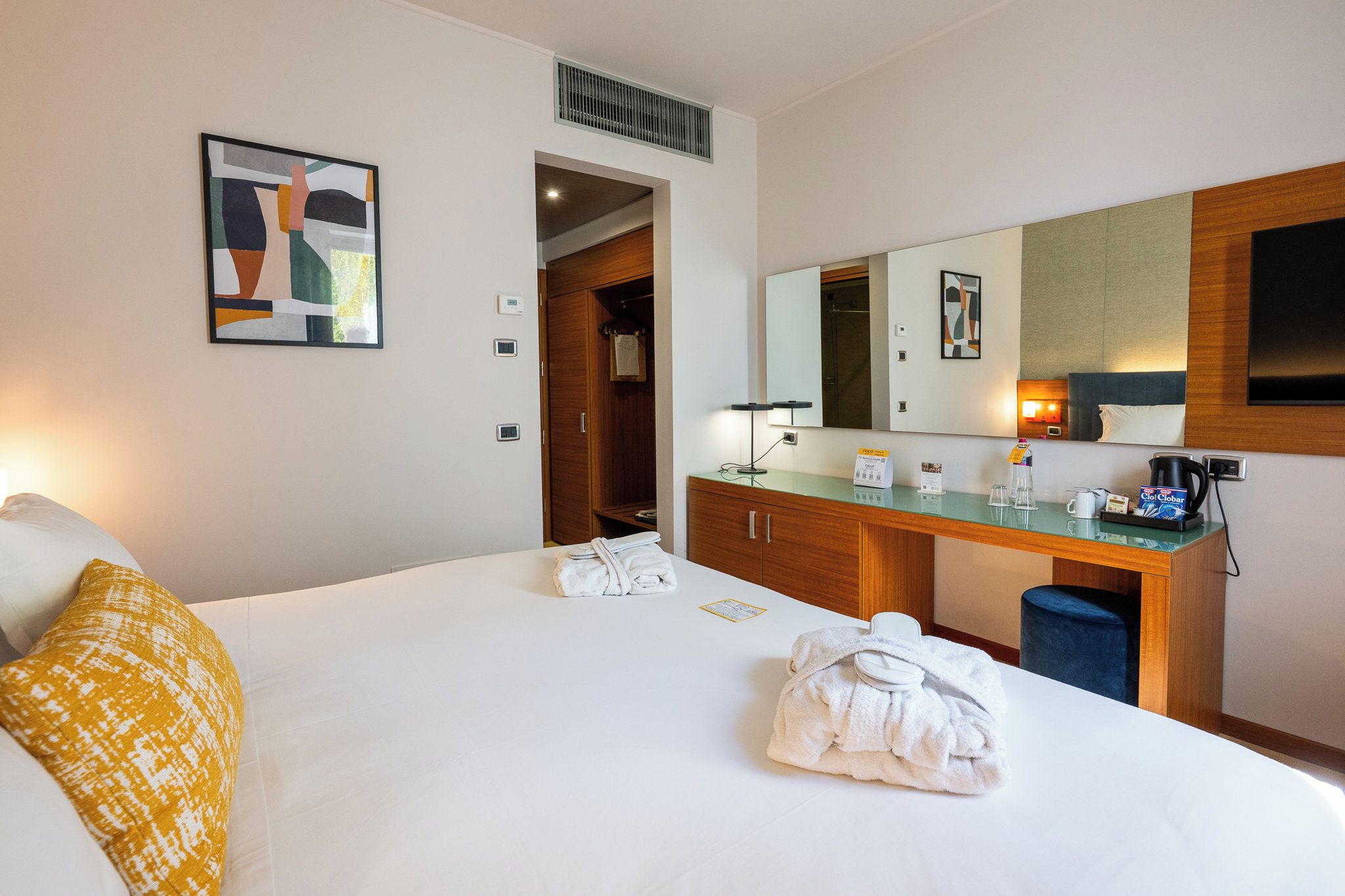 Habitació d'hotel amb un llit, escriptori, mirall i porta al bany.
