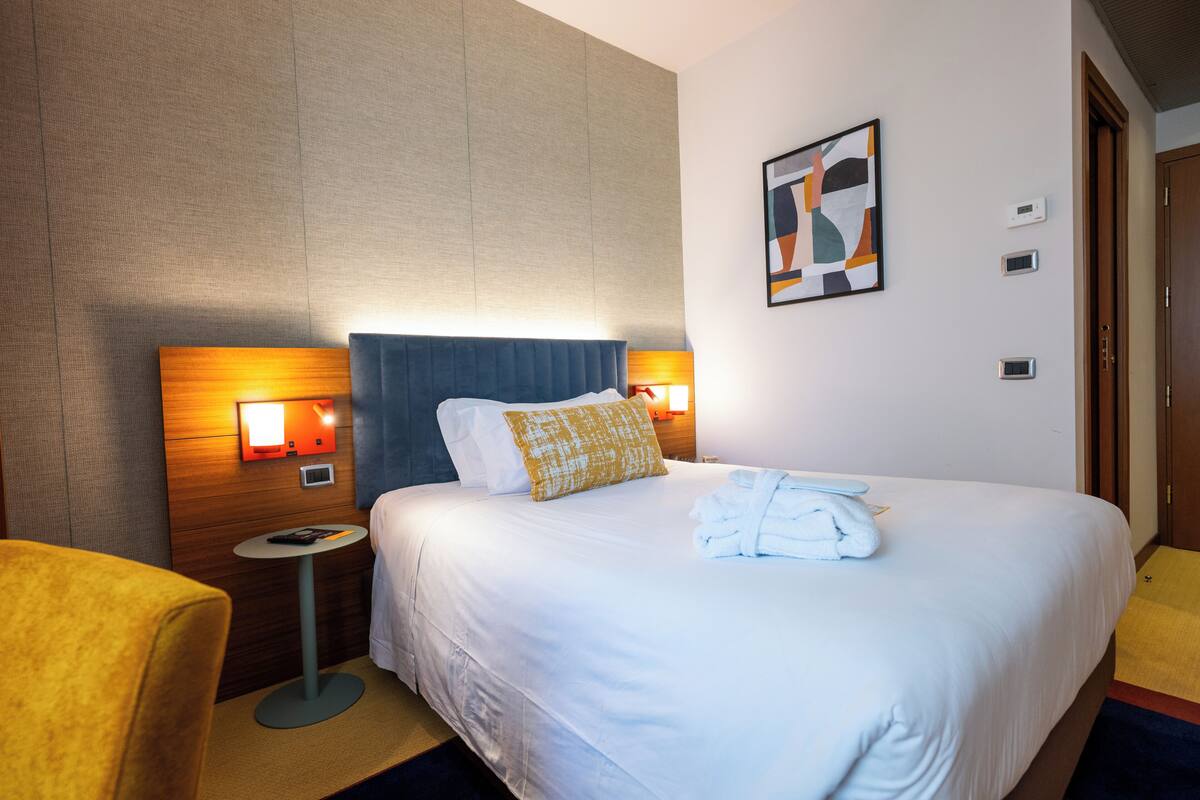 Une chambre d’hôtel avec un grand lit, des lampes de chevet, une petite table et une chaise.