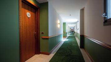 Un pasillo de hotel con alfombra verde, puertas de madera y un cartel que indica el número de habitación 138.