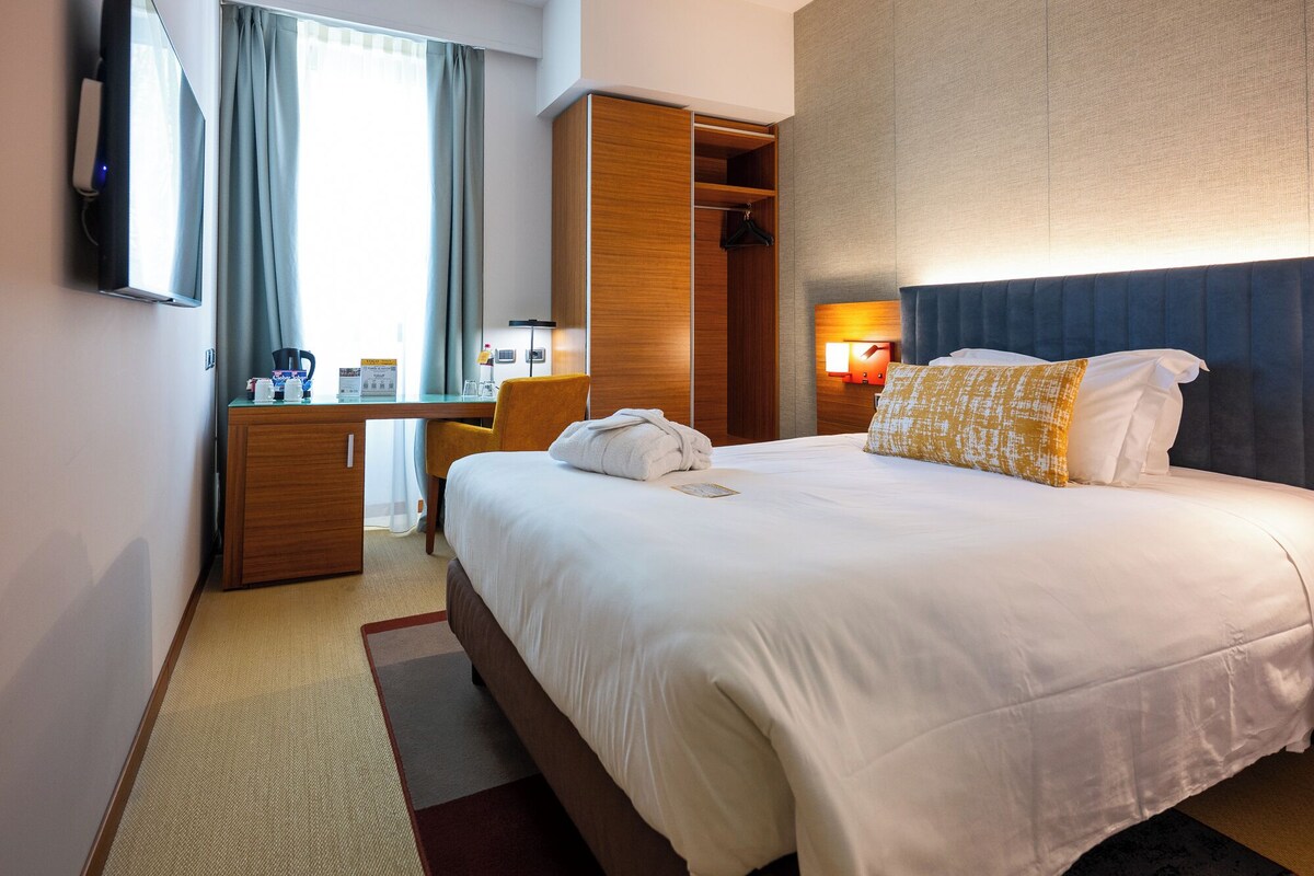 Une chambre d’hôtel avec un lit, un bureau, une armoire et un téléviseur.