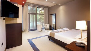 Una habitación de hotel con cama, mesita de noche, lámpara y televisor montado en la pared.