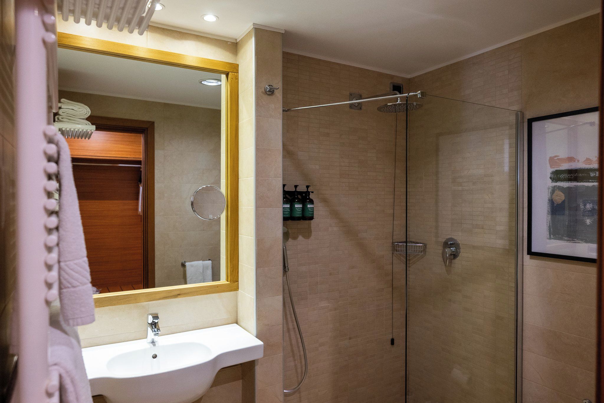 Baño con lavamanos, espejo, ducha y artículos de aseo.
