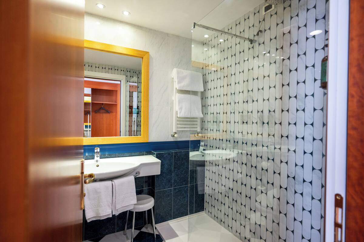 Une salle de bain moderne avec une douche à parois de verre, un lavabo et un miroir.