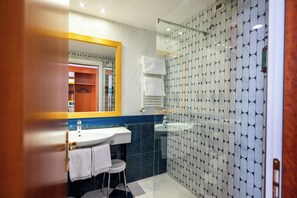 Un baño moderno con cabina de ducha de vidrio, un lavabo y un espejo.