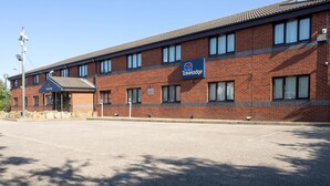 A Travelodge hotel with a brick facade, large windows, and a clear sky. - Travelodge Sedgefield (Stockton-on-Tees)